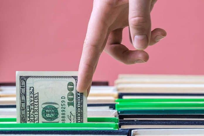 Fingers,Pulling,Money,Out,Of,Book,Pages,,Rows,Of,Books